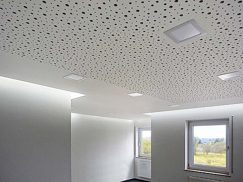 Innenansicht eines Raumes mit weiß gestrichenen Wänden und einer Decke aus perforierten Akustikplatten (Trockenbau) zur Schallabsorption.