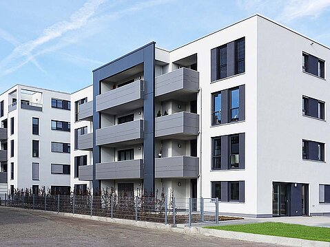 oderne Mehrfamilienhäuser mit weißem Fassadenputz und dunklen Akzenten an den Balkonen. Beispiel für fachgerecht ausgeführte Wärmedämmung (WDVS).